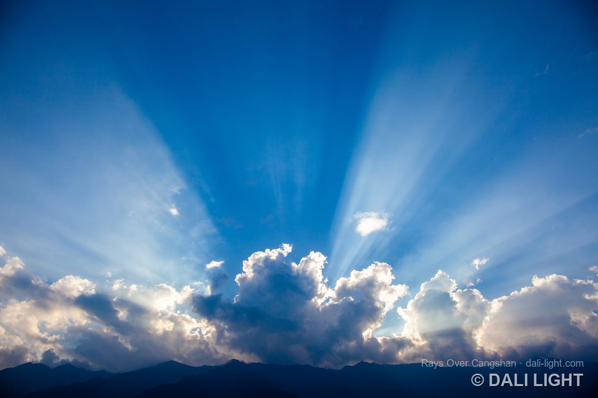 Crepuscular rays bursting through clouds above the Cangshan mountains, Dali